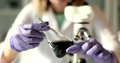 Laboratory assistant scientist holds test tubes and examines oil products Stock Footage 232217484