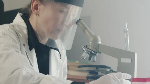 A laboratory assistant in a white coat and with a protective screen on her face Stock Footage 241666603