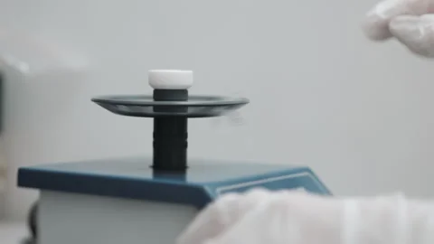 A laboratory assistant in white gloves puts Eppindorf into a laboratory mixer. Stock Footage 294561124