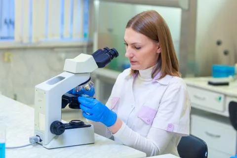 Laboratory assistant working with a microscope in a scientific laboratory. Stock Photos
