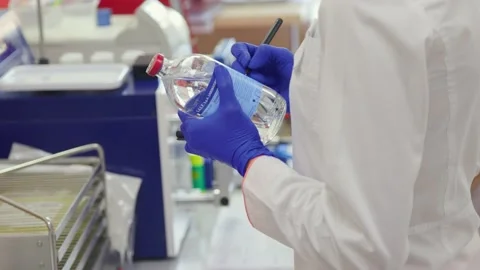 Laboratory assistant writes on a bottle with clear luqid Stock Footage 234813621