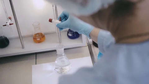 Laboratory beaker in analyst's hand in plastic glove. Vidéo 76739810