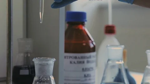 Laboratory beaker in analyst's hand in plastic glove. Stockbeeldmateriaal 76740718