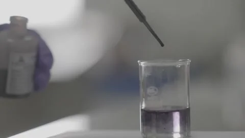 Laboratory experiment adding drops of reagent to a purple solution Stock-Footage 327451814