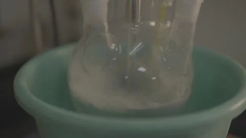 Laboratory flask mixing white liquid in a cooling bath Stock-Footage 327633361