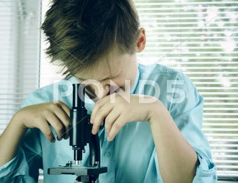 Laboratory. funny boy intently looking through a microscope. close-up Stock Photos