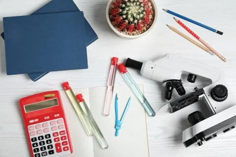 Laboratory glassware, microscope and school supplies on wooden background, fl Stock Photos