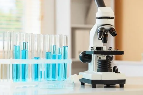 Laboratory microscope and test tubes with blue liquid for scientific research Stock Photos