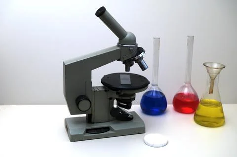 Laboratory microscope with flasks of colored liquids on white background Foto stock