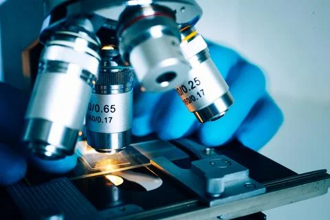 Laboratory optical microscope macro view with gloved hands Stock Photos