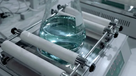 Laboratory roller mixes solution in glass flack for products in medicine Stock Footage 187453921
