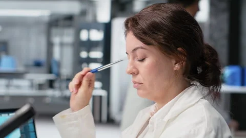 Laboratory scientist brainstorming ideas at computer desk, rubbing pen on chin Stock Footage 320143913