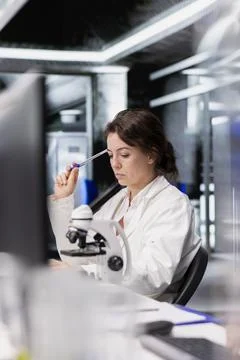 Laboratory scientist brainstorms ideas, using PC to process DNA patient data Stock Photos