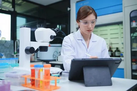 Laboratory Technician Conducting Analysis with Microscope and Tablet Фото