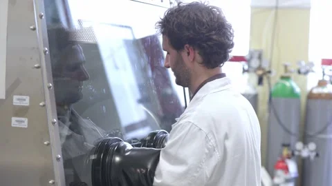 Laboratory technician doing dangerous experiment with protective special box and 库存影片 250007505