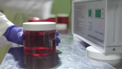 Laboratory Technician Handling a Sample Jar in a Controlled Environment for Stock Footage 307618044