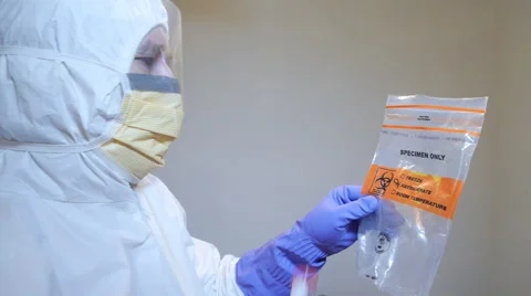 Laboratory technician placing specimen into bio-hazard bag. Stock Footage 60070446