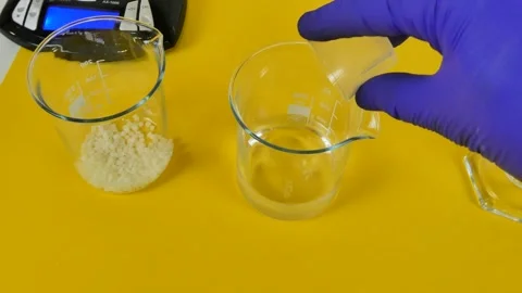 Laboratory technician pouring an ingredient and stirring a mixture in a beaker Stock Footage 334811592