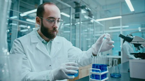Laboratory Technician Pouring Liquid into Test Tubes for Chemical Experiment Видео 331337633