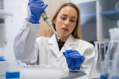 Laboratory technician transferring liquid samples into microcentrifuge tubes at Foto stock