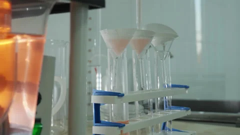 A laboratory technician in a white coat and protective gloves pours liquid into Stock Footage 333461677