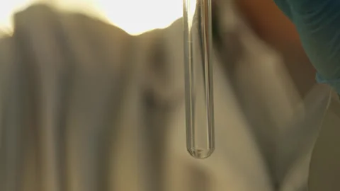 A laboratory technician in a white coat and protective gloves pours liquid into Stock Footage 333461748