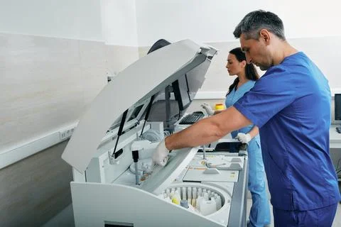 Laboratory technicians analyze blood samples near biochemical automatic blood Photos