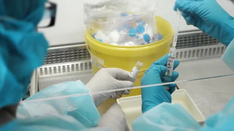 Laboratory technicians handling sample tubes in sterile medical lab. 스톡 동영상 347778760
