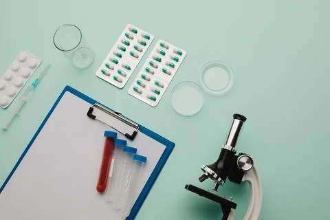 Laboratory test. Microscope, pills, test tube on blue background Stock Photos