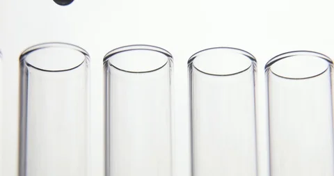 Laboratory test. Pipette drips transparent chemicals into a four test tubes on Stock Footage 106200780