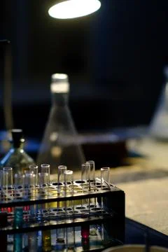 Laboratory test tubes arranged in a rack with glass flasks and a lamp illum.. Stock Photos