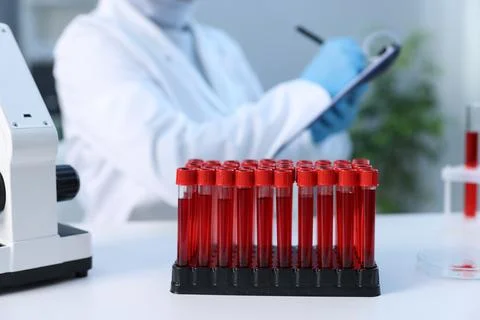 Laboratory testing. Doctor taking notes at table indoors, focus on test tub.. Fotos Stock