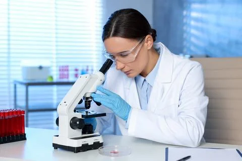Laboratory testing. Doctor working with microscope at table indoors Stock Photos