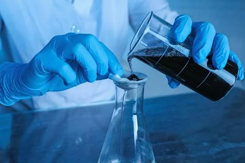 Laboratory testing. Scientist filtering soil sample at table indoors, closeup Stock Photos