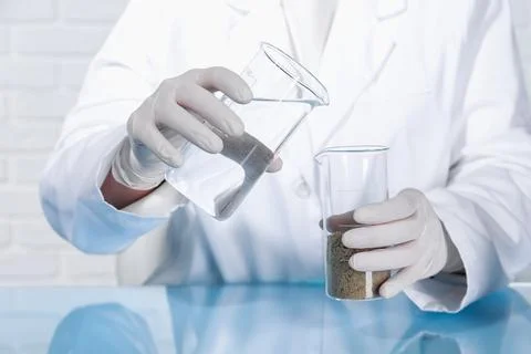 Laboratory testing. Scientist pouring liquid into beaker with soil sample a.. Foto stock