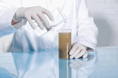 Laboratory testing. Scientist pouring liquid into beaker with soil sample a.. Foto stock