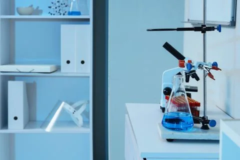 Laboratory workbench with microscope, flask containing blue liquid, and test  Stock Photos