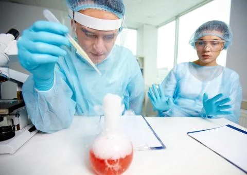 Laboratory worker is about to inject fluid into chemical substance during experi Stock Photos