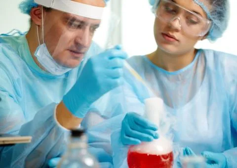 Laboratory worker is about to inject fluid into chemical substance during experi Stock Photos