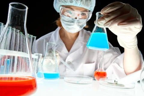 Laboratory worker looking at bottle with liquid during scientific experiment in Stock Photos