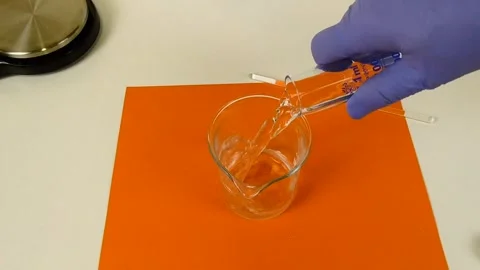 Laboratory worker in protective gloves pouring a solution from a graduated Stock Footage 337738050
