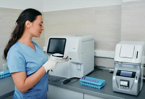 Laboratory worker scanning barcode of test tube with blood on her workplace n Stock-Fotos