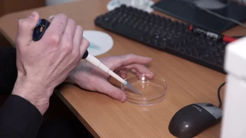 Laboratory worker sits at table, holds test-tube, pipette in hand in office Stock Footage 76596634