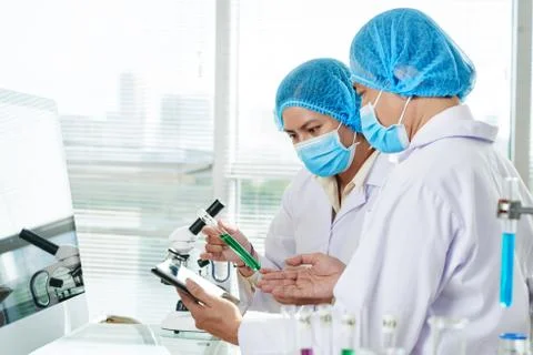 Laboratory workers with test-tube of green liquid Stock Photos