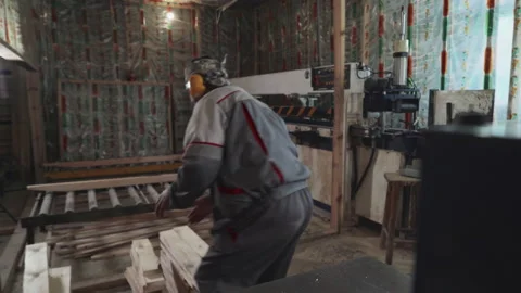 Laborer is placing stack of timber planks into the machine for processing by saw Stock Footage 171672573