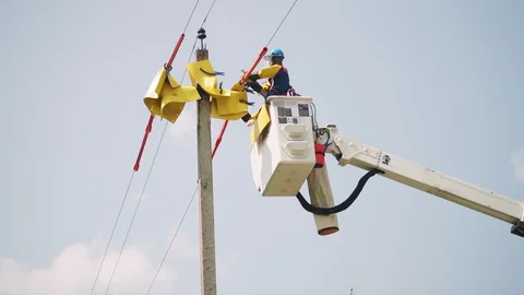 Laborer puts yellow sheets onto power line cables in basket 스톡 동영상 127758317