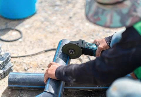 Laborer using an electric grinding tool to cut and shape high-density polye.. Stock Photos