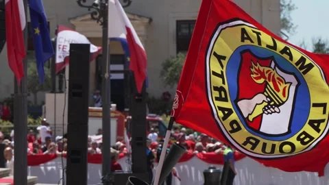 A Labour Party flag waves over a gathering near Auberge de Castille in Valletta Stock Footage 336488477