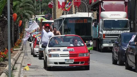 Labour supporters in Valletta wave red and Maltese flags at a motorcade Video stock 336491264