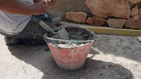 Labourer working on construction site with orange stones laying with cement mix Stock Footage 164596706